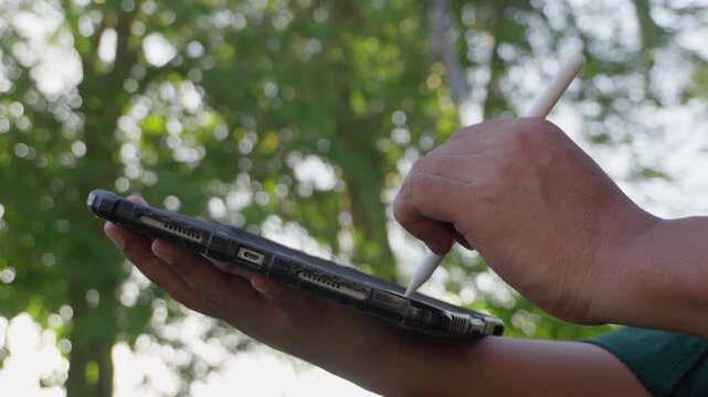 Business professional using digital tablet with stylus outdoors in natural environment for business planning, paperless workflow, sustainable technology, digital transformation, creative productivity