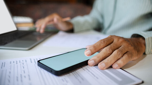 close-up shot, hand of businessman using mobile phone work on desk with laptop and document. meeting  and work online via wireless technology