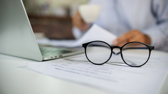 close-up shot, select focus at eyeglasses and blurred people working with laptop in background