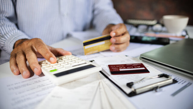 close-up shot, asian man using calculator to calculate credit card expenses, checking receipt and bills before pay