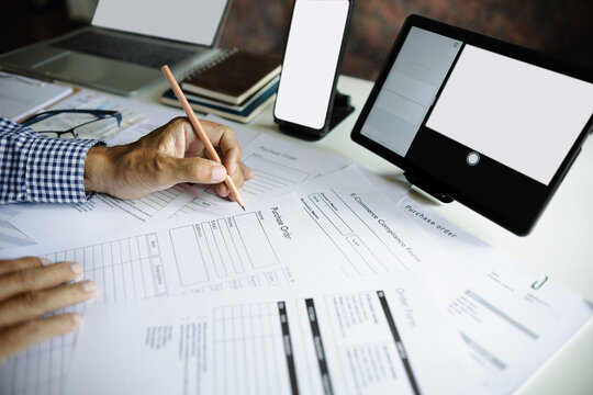 asian man working online via laptop, tablet and mobile phone checking e-commerce form and order from customers, e-commerce online business concept