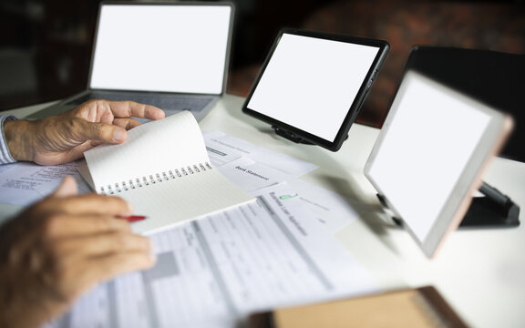 close up shot, hand of businessman working and meeting online with digital tablet checking business contract, various documents and taking note working at home to start e-commerce business