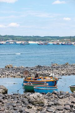 Local fisherman in coracle basket boat anchored on shallow coastal rock shelf at Phuoc Thien during summer midday with copy space