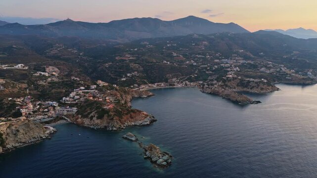 Aerial drone view of a rugged coastline with rocky coves below mountains, Agia Pelagia, Greece