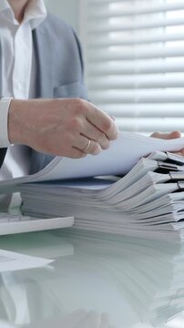 Business professional hands actively managing a large stack of office documents. Reports. And paperwork. Representing administrative work. Corporate bureaucracy