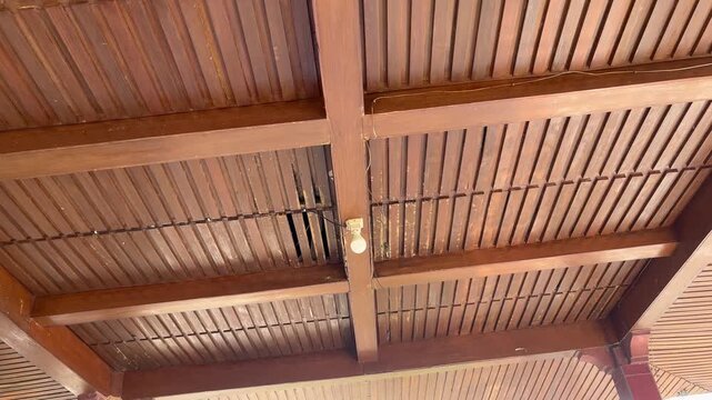 Traditional Javanese wooden ceiling architecture with hanging light bulb