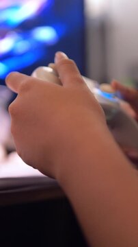 Vertical video Close-up of hands holding a game controller while playing video games at home. For gaming, entertainment, esports, leisure, and modern lifestyle concepts