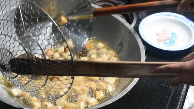 Close-up of frying colorful Indonesian crackers in hot oil. Traditional snack preparation featuring vibrant crackers, authentic local cuisine, homemade cooking, crispy texture, and delicious street fo
