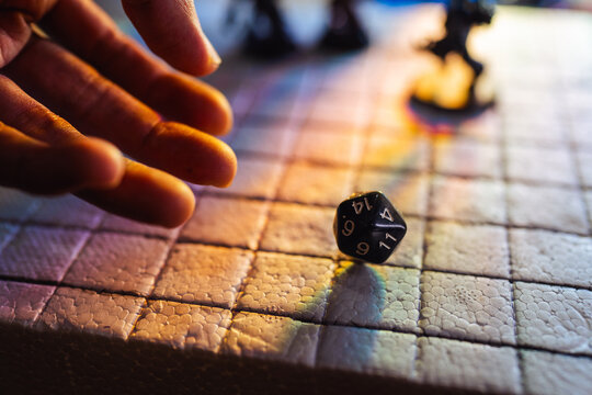 Hand Rolling a D20 Dice While Playing a Fantasy Tabletop Roleplaying Board Game