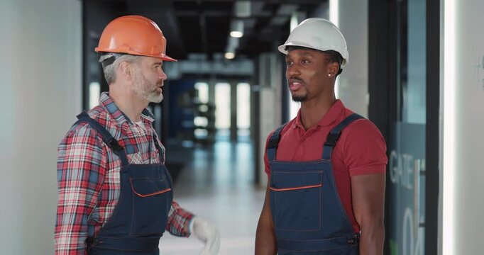 Two construction workers are engaged in a conversation about their ongoing project tasks and plans