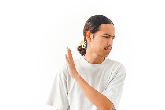 Young man with a hair clip making a stop or rejection gesture with his hand isolated on white background.