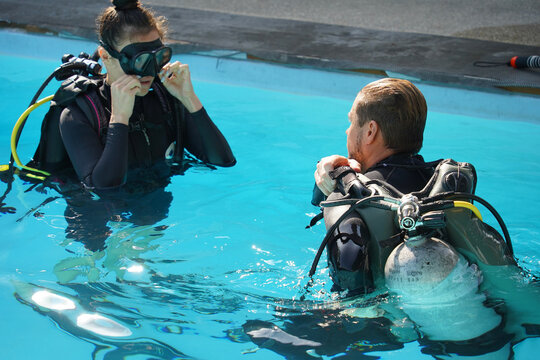 Professional scuba diver instructs the novice how to use the equipment before dive
