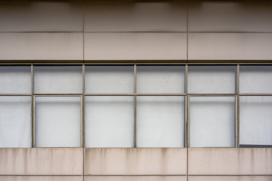 Modern building facade with large frosted glass windows and concrete panels creating a minimal geometric architectural background.