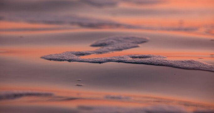 Vibrant Pink and Purple Sea Foam Reflections on Wet Shoreline