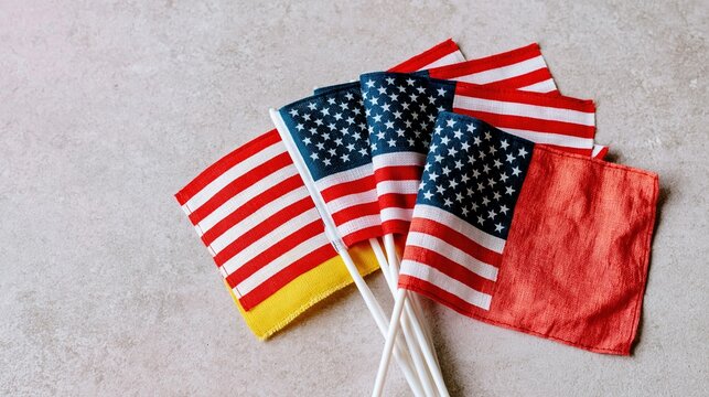Small American flags fanned on a textured neutral surface with weathered fabric and soft light for Veterans Day and patriotic remembrance concepts