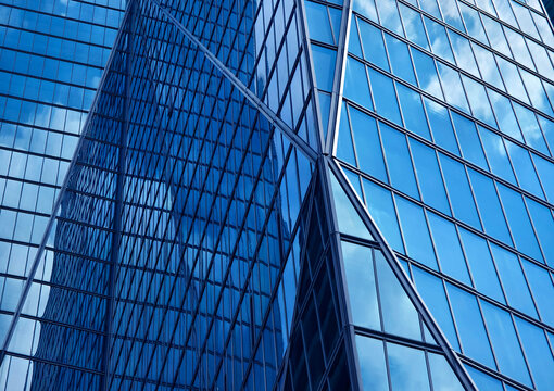 Urban skyscraper with mirrorlike surfaces showcasing clouds and geometric patterns