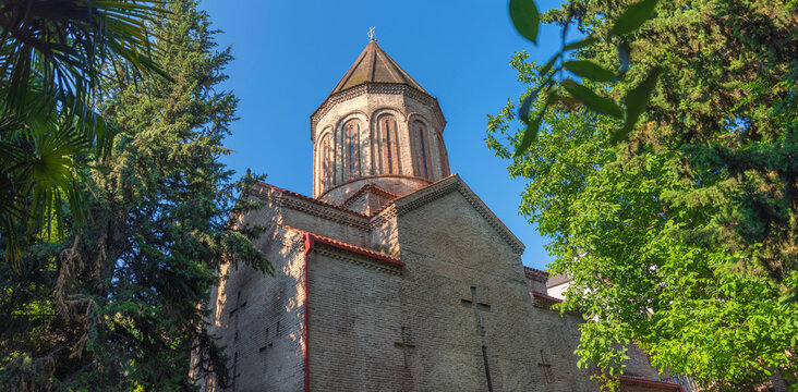 Ancient Surb Gevorg brick cathedral in old Tbilisi with trees framing and copy space