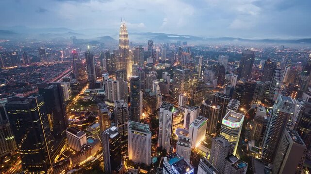 Asia, Malaysia, day to night transition zoom in time lapse of the Kuala Lumpur skyline and financial district at dusk, showing skyscrapers and the Petronas towers, high angle view