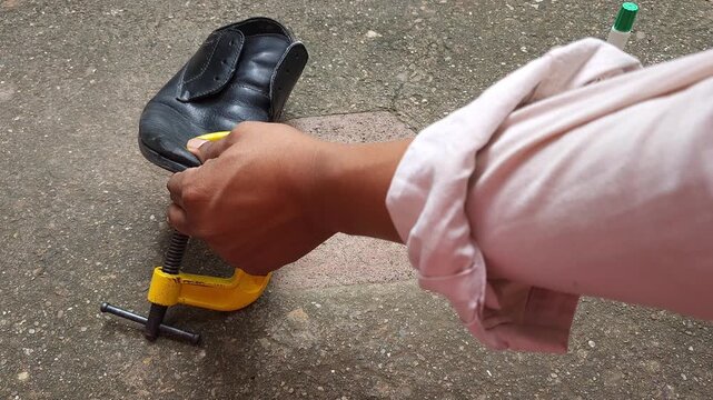 Pressing a detached shoe sole firmly with hand to ensure glue adhesion.