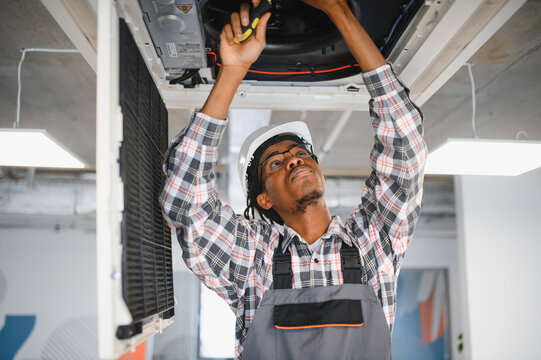 Skilled technician repairing ceiling mounted air conditioning unit
