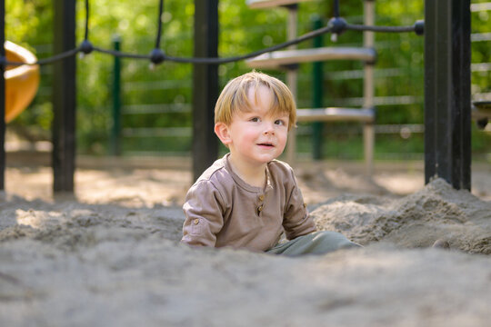 Smiling Toddler Sitting In Sandbox