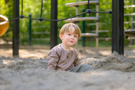 Happy Toddler Sitting In Sandbox