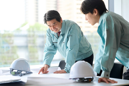 打ち合わせをする作業服を着た男性