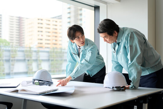 打ち合わせをする作業服を着た男性