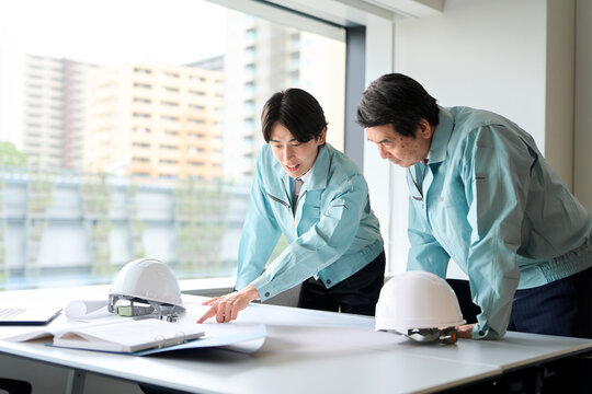 打ち合わせをする作業服を着た男性