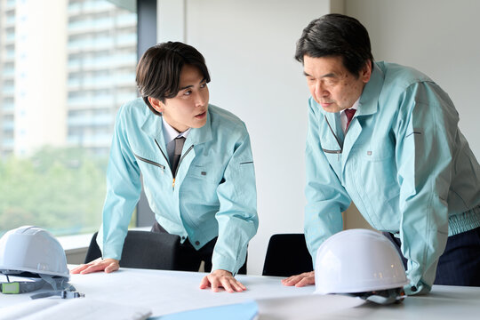 打ち合わせをする作業服を着た男性