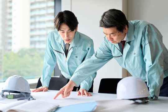 打ち合わせをする作業服を着た男性
