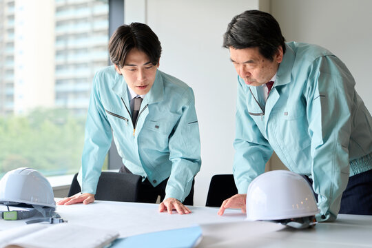 打ち合わせをする作業服を着た男性