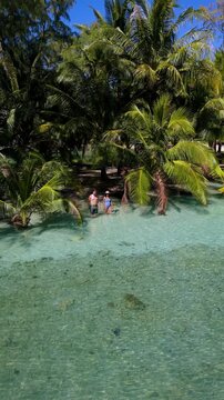 Explore the beauty of Koh Kood, Thailand, as two travelers wander through calm, turquoise waters surrounded by swaying palm trees. Experience paradise in every step.
