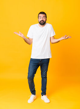 Full-length shot of man with beard over isolated yellow background making doubts gesture