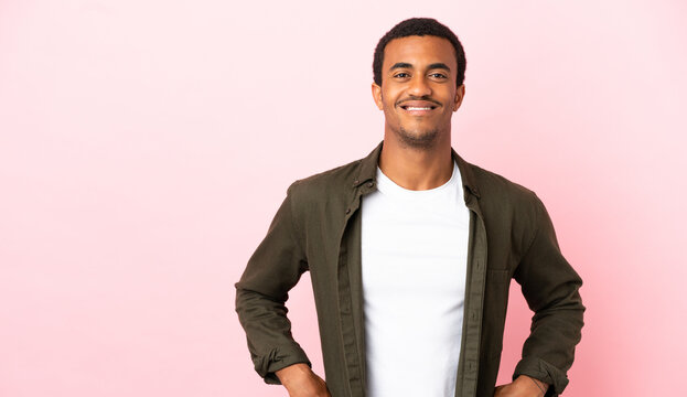 African American man on copyspace pink background posing with arms at hip and smiling