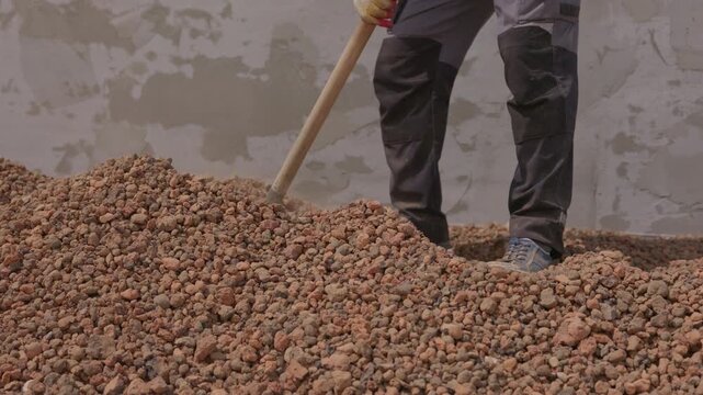 Leveling expanded clay aggregate insulation on flat roof with shovel