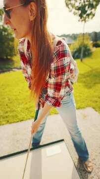 Playing mini golf in an outdoor park on a sunny day with friends near a green landscape