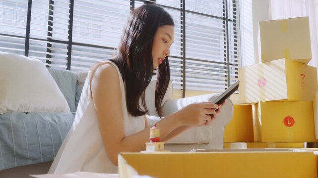 Young Asian woman happy and smiling unpack boxes at new house, relocation and people in real estate or apartment. Moving house concept