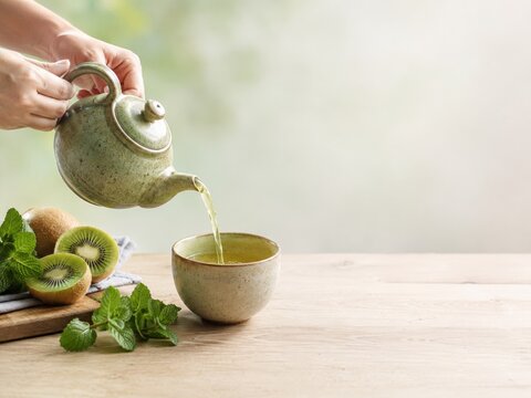 T&eacute; verde se sirve desde una tetera en un cuenco con frutas y hojas de menta