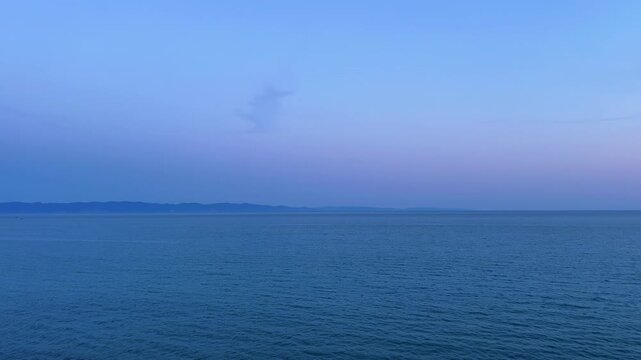 Beautiful wide static shot of calm sea water with gentle ripples under a colourful twilight sky in Edirne, Turkey.