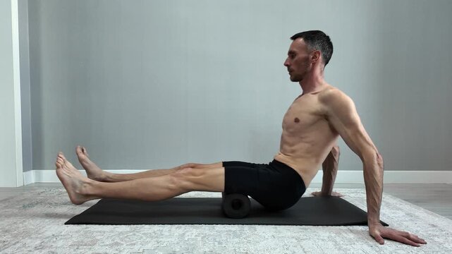Fit man performing myofascial release with foam roller