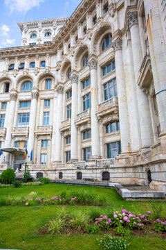 Side facade and entrance steps of the Palace of the Parliament with green garden in Bucharest Romania