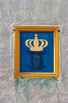 Royal monogram emblem with crown on white wall