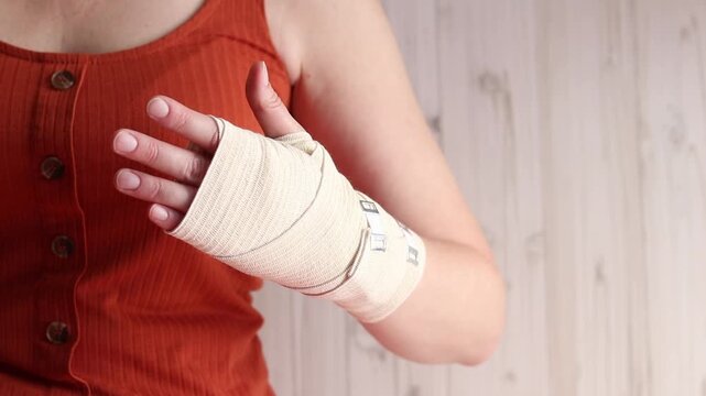 Woman with elastic compression bandage on wrist and palm. Medical care for joint pain, sports injuries or arthritis. Female hand with elastic bandage on wrist, close-up. Hand in medical bandage