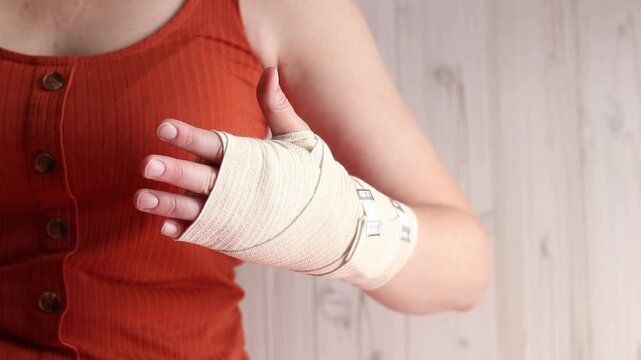 Woman with elastic compression bandage on wrist and palm. Medical care for joint pain, sports injuries or arthritis. Female hand with elastic bandage on wrist, close-up. Hand in medical bandage