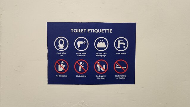A blue and white restroom etiquette sign mounted on a wall detailing rules such as flush after use, place bidet after use, and no smoking