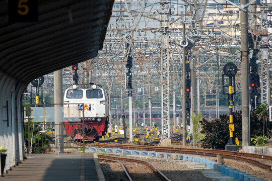 Jakarta, Indonesia - July 02, 2026: A KAI diesel locomotive stands on the tracks near the platform at Jakarta Kota Station beneath overhead catenary wires and railway signals.
