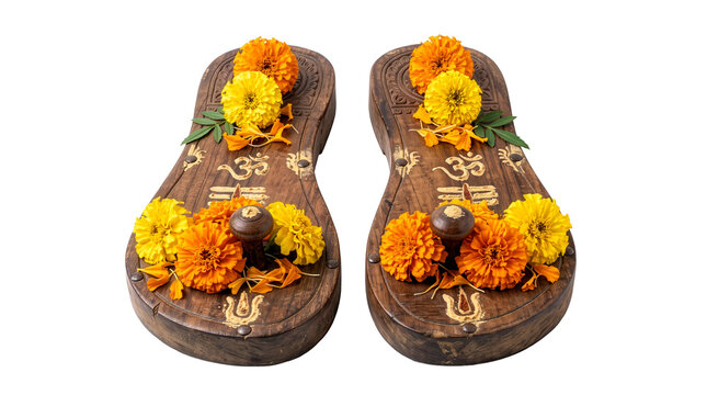 Traditional carved wooden Guru paduka sandals adorned with fresh orange and yellow marigold flowers, isolated on a transparent background