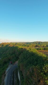 Vertical video. Smooth Cinematic Aerial Flight Above Deep Cliff Passage At Pantai Tanah Barak, Sunrise Light Illuminating Green Fields And Coastal Terrain, Progress And Discovery