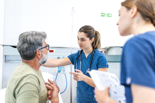 female doctors explaining medical diagnosis to older male patient in hospital room after successful operation. Skilled physician talking with man. Healthcare, clinical medicine and recovery program.